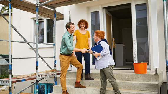 Brakle startbild  Happy real estate agent shaking hands with potential new home buyers.