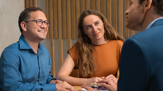 Brakle startbild  Happy real estate agent shaking hands with potential new home buyers.