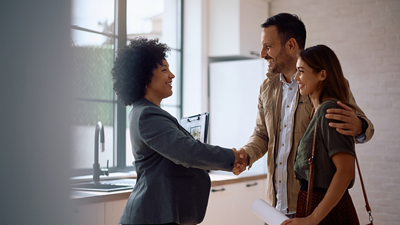 Brakle startbild  Happy real estate agent shaking hands with potential new home buyers.